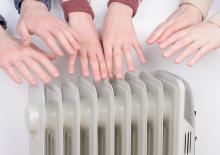 Cold people inside of a home reaching for a heater because it is so cold in Lawton, OK