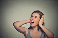 Woman covering her ears to block out noise. Can often be caused by a loud or noisy furnace