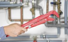 wrench being held by repairman getting ready to service air conditioner