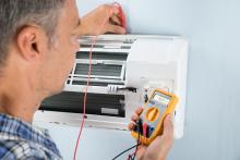 Technician measuring temperature of mini split with HVAC thermometer