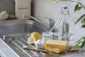 Cleaning solutions next to sink like lemon, baking soda, toothbrush, and sponges
