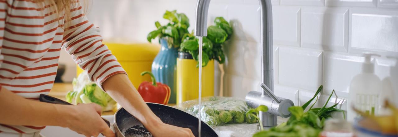 woman washing a pan in her kitchen sink