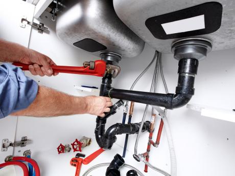 Plumber repairing pipes under sink