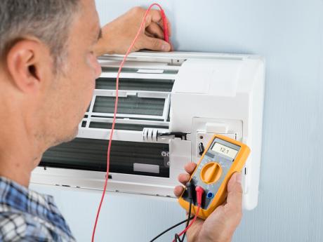 Technician measuring temperature of mini split with HVAC thermometer