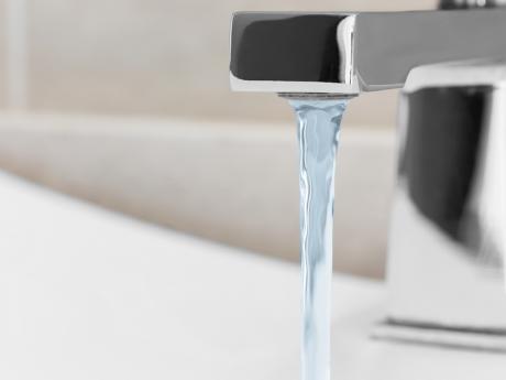 Water coming out of polished silver faucet Water coming out of polished silver faucet