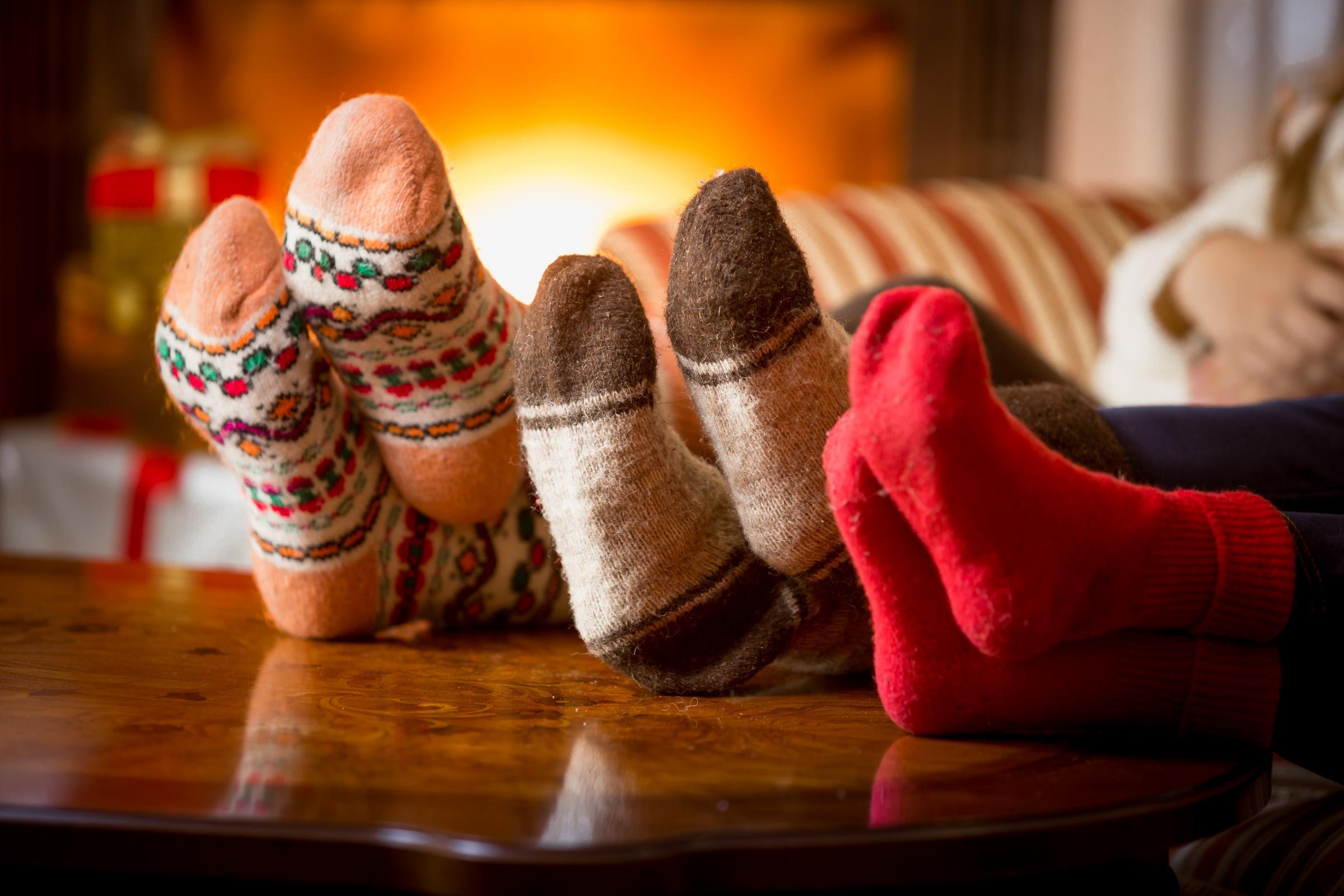 family's socked feet in front of a fire