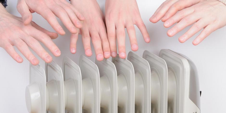 Cold people inside of a home reaching for a heater because it is so cold in Lawton, OK