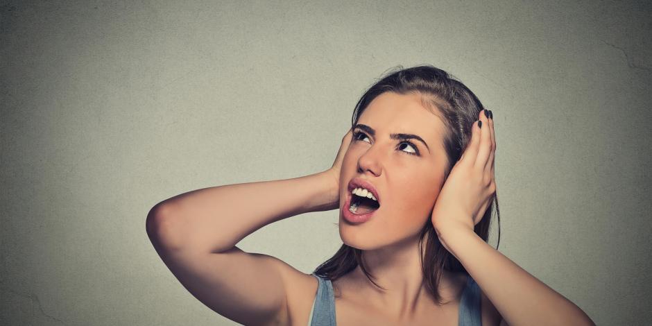 Woman covering her ears to block out noise. Can often be caused by a loud or noisy furnace