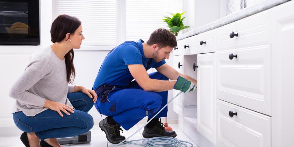 Technician cleaning drain while homeowner watches