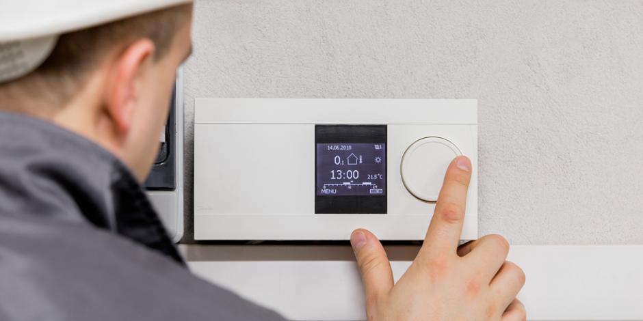 Technician tinkering with thermostat Pippin Brothers Heating & Cooling Oklahoma