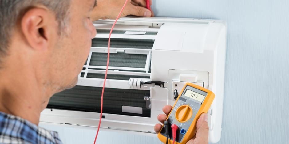 Technician measuring temperature of mini split with HVAC thermometer Technician measuring temperature of mini split with HVAC thermometer