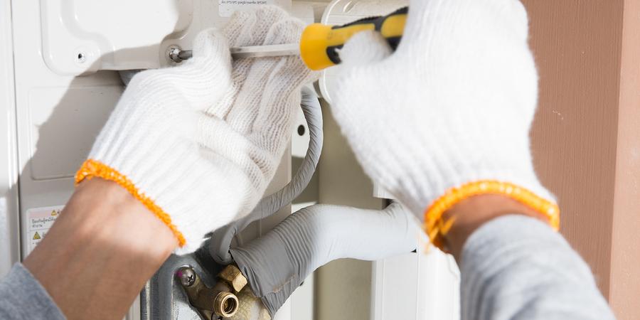 Gloved hands repairing air conditioner with screwdriver Gloved hands repairing air conditioner with screwdriver