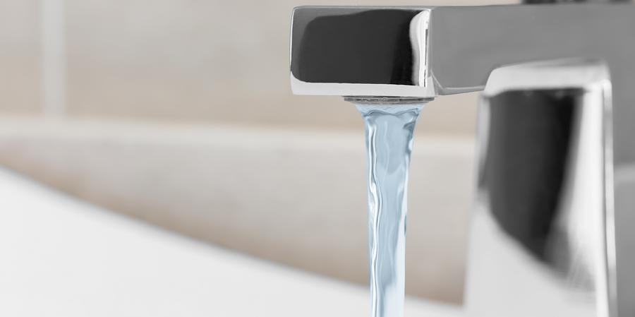 Water coming out of polished silver faucet Water coming out of polished silver faucet